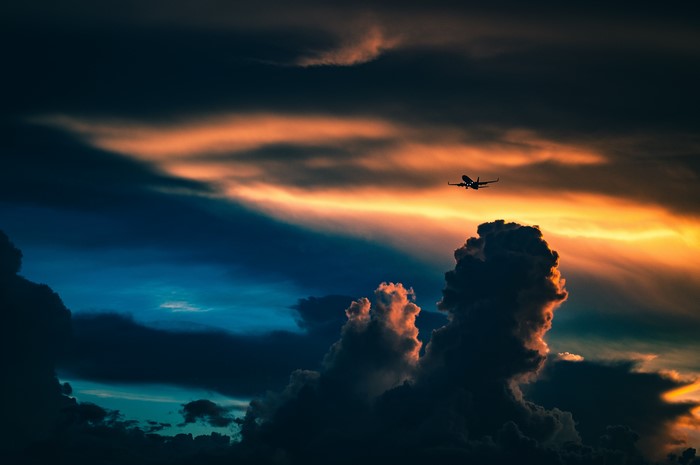 Airplane flying through sunset clouds