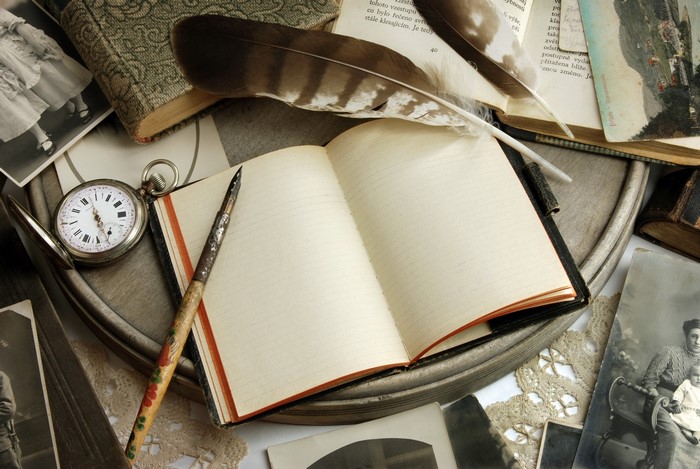 Vintage notebook with quill, pocket watch, and old photographs