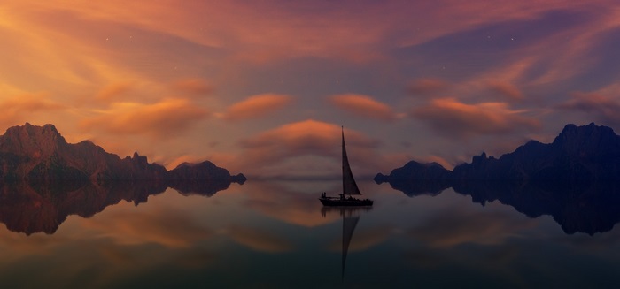 Sailboat on a lake with mountains at sunset