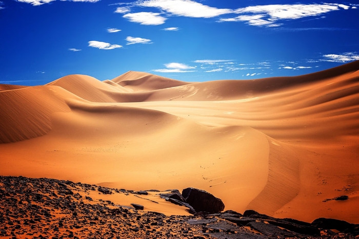 Desert dunes and rocks under a blue sky
