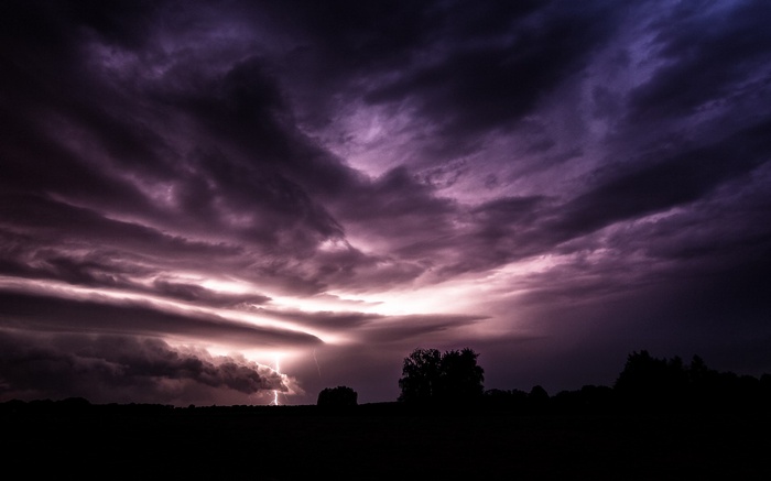 Lightning strike over silhouetted landscape at dusk