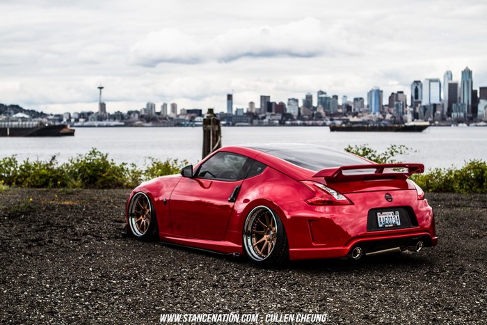 Red Nissan 370Z parked by the water with city skyline