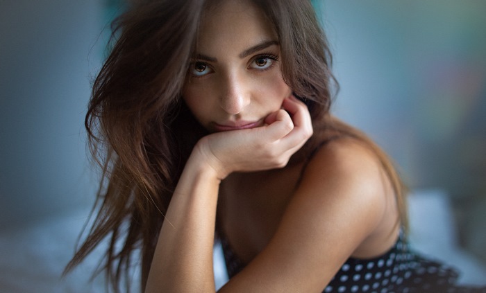 Woman with brown hair and brown eyes resting chin on hand
