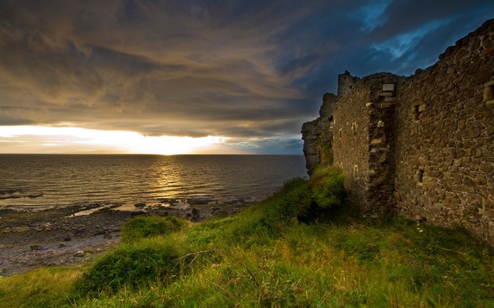 Castle ruins on a cliff overlooking the sea at sunset