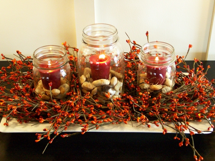 Thanksgiving centerpiece with candles in mason jars and berry garland