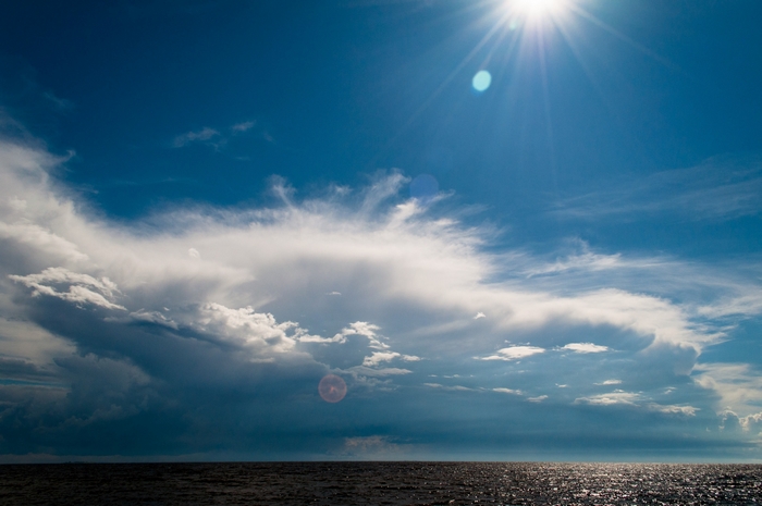 Sun shining over the ocean with dramatic clouds