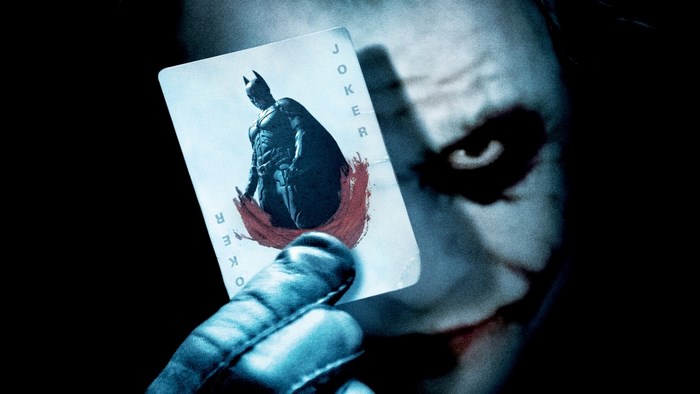 The Joker holding a Joker card with Batman on it