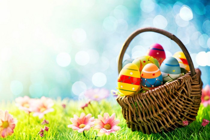Easter eggs in a basket on grass with flowers