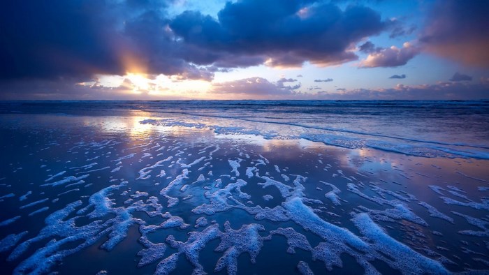 Ocean waves and foam at sunset