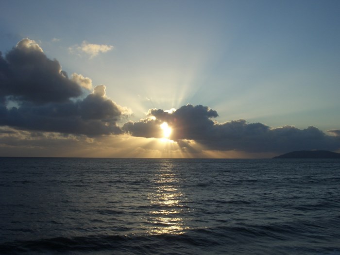 Sunset over the ocean with clouds and island