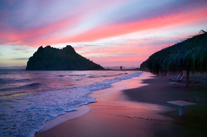 Sunset over a tropical beach with a rocky island