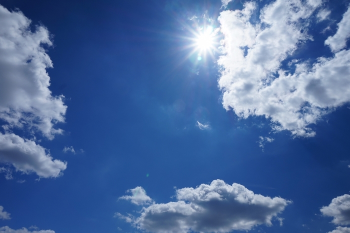 Bright Sun Shining Through Clouds in Blue Sky