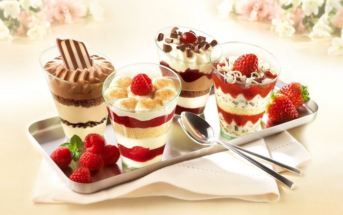 Four desserts on a tray with berries