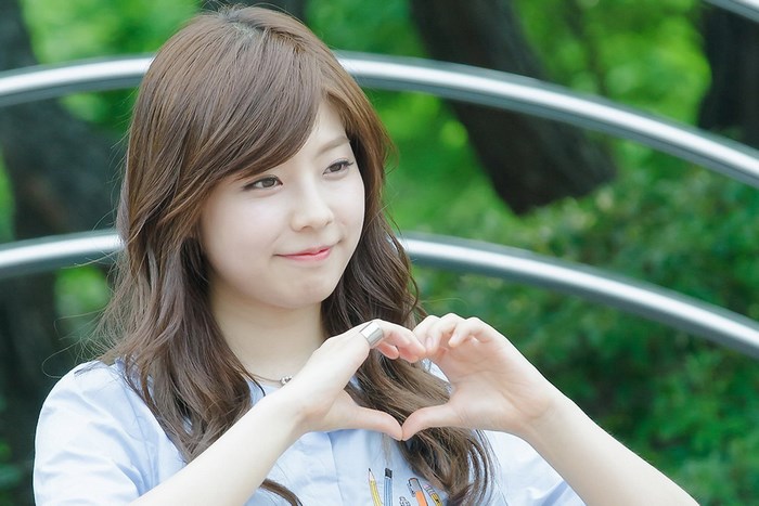 Korean Girl Forming Heart with Hands Outdoors