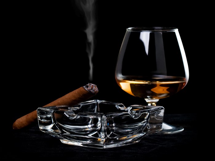 Whisky Glass with Smoldering Cigar on Ashtray