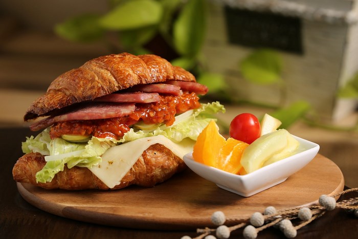 Croissant sandwich with ham, cheese, lettuce, and fruit salad