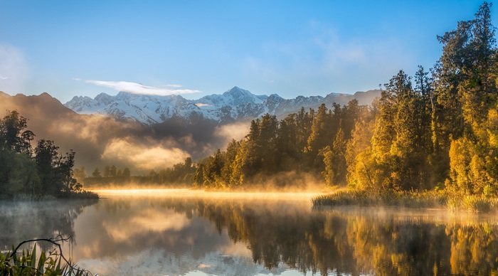 Misty Lake with Snow-Capped Mountains and Autumn Forest
