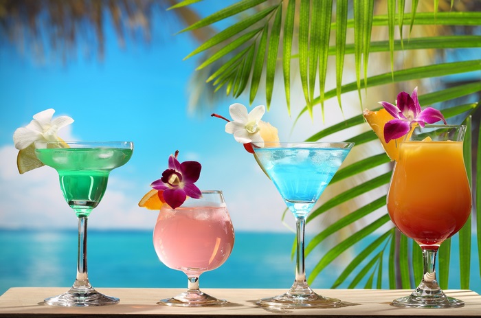 Four tropical cocktails on a table with a beach background