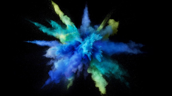 Explosion of blue, green, and yellow powder on black background