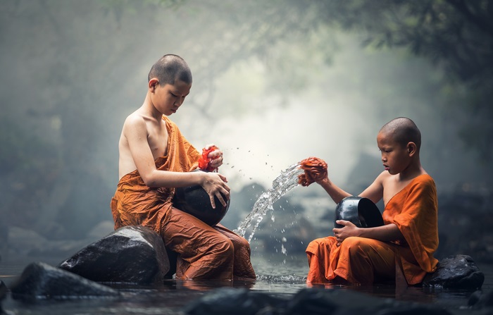 Two young monks washing bowls in a stream