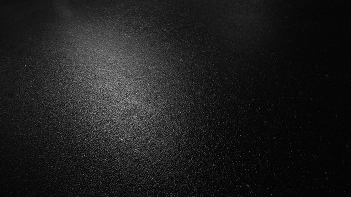 Dark black textured surface with light reflection