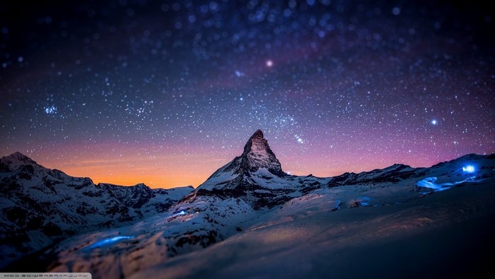 Snowy mountains under a starry night sky