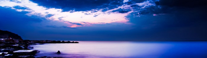 Dual screen landscape with dark clouds over the ocean
