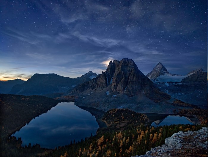 Starry night over mountains and lake in fall