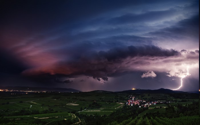 Lightning storm over a village and vineyards