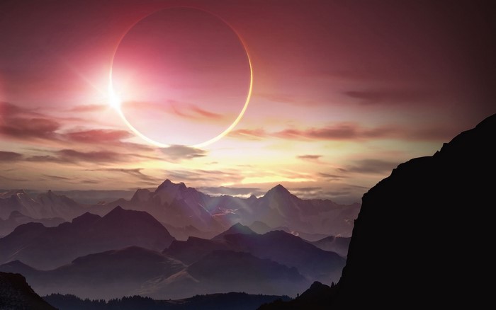 Solar eclipse over mountain range at sunset