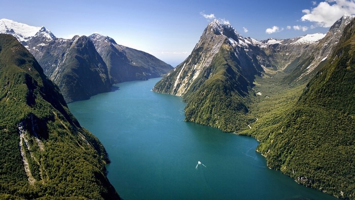 Milford Sound, New Zealand, with snow-capped mountains and a boat