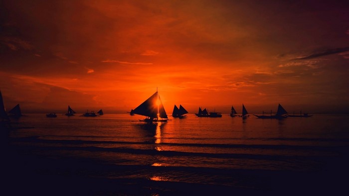 Sailboats on the sea during sunset with red sky