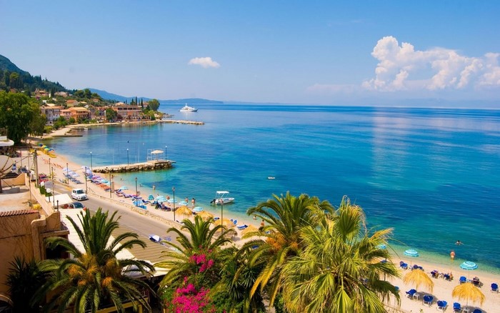Beach town with palm trees and blue sea in Greece