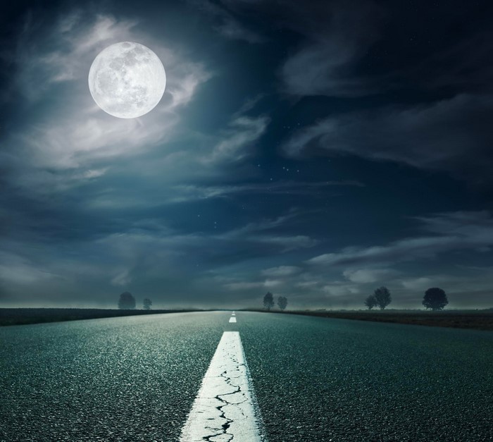 Empty highway at night under a full moon