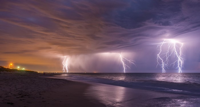 Lightning strikes over the ocean at a beach