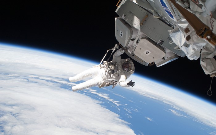 Astronaut on spacewalk near International Space Station over Earth