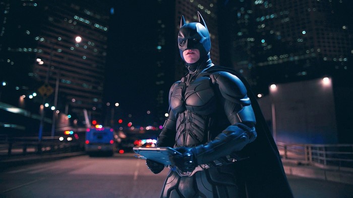 Batman from The Dark Knight Rises holding a tablet