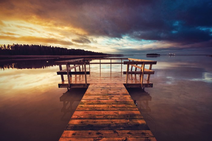 Wooden pier on a lake at sunset with dramatic clouds