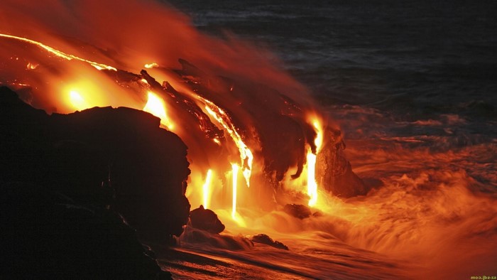 Lava flowing into the sea at night