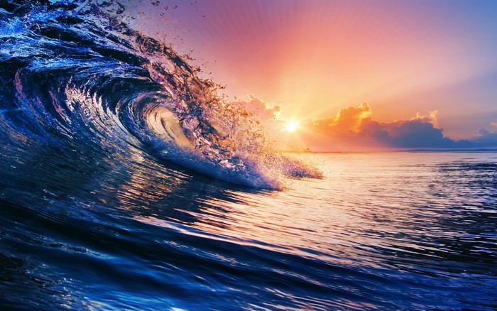 Ocean wave crashing at sunset with colorful sky