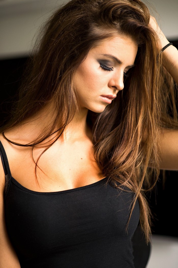 Woman with long brown hair wearing a black tank top