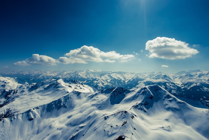 Snow-covered mountains under a blue sky with clouds