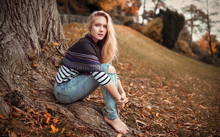 Woman with blonde hair sitting by a tree