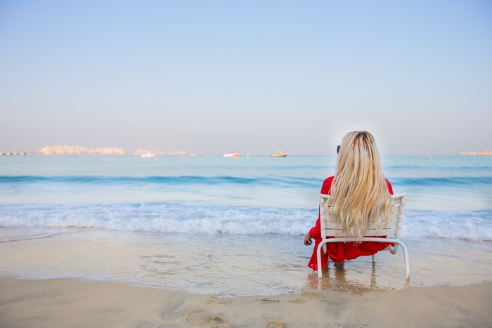 Woman in red dress sitting on a chair at the beach