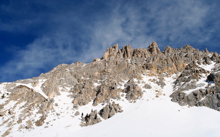 Snow-covered rocky mountain range under a blue sky