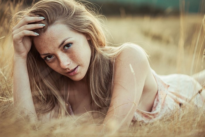 Woman with freckles lying in a field