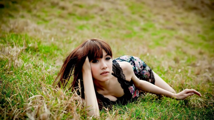 Woman with long brown hair lying in grass