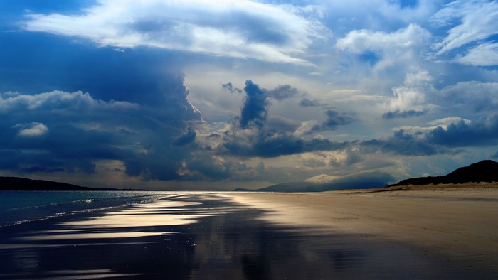 Beach with dramatic clouds and reflections