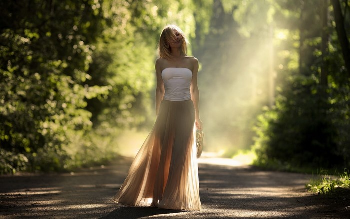 Woman in white top and flowing skirt walking in sunlight