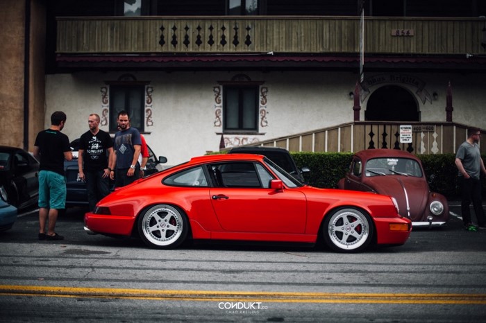 Red Porsche 911 and Volkswagen Beetle with people